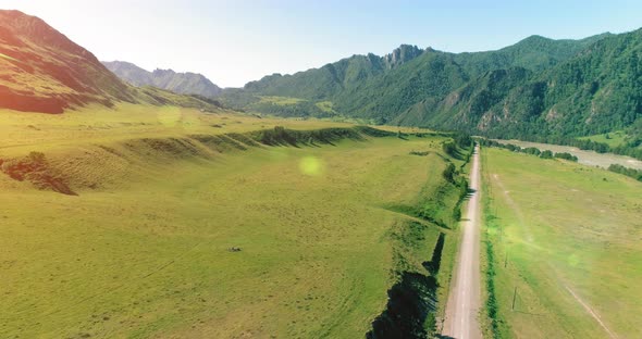 Aerial Rural Mountain Road and Meadow at Sunny Summer Morning. Asphalt Highway and River.