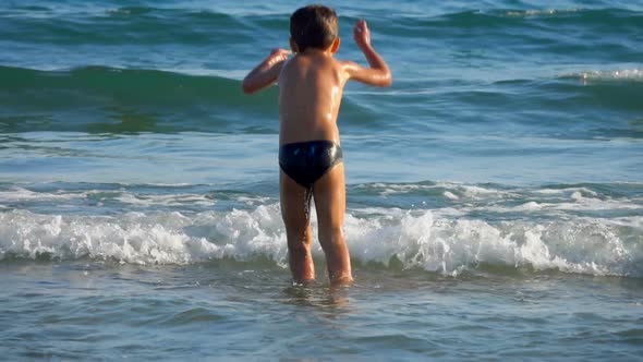 The Little Boy is Jumping in the Sea Waves