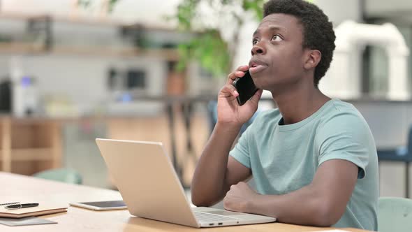 Young African Man Using Smartphone and Laptop