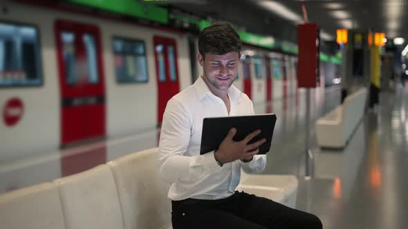 Glad Businessman Using Tablet in Subway