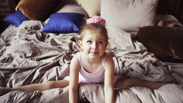 Cute Baby Girl Blonde in Bed Sitting in the Splits and Smiling