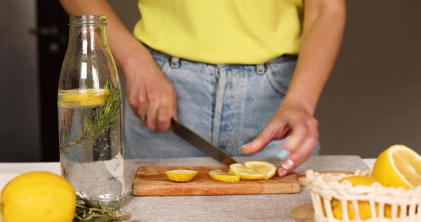 Female Hand Cut Lemon Making Detox Healthy Water with Lemon and Rosemary