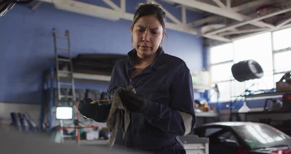 Female mechanic cleaning equipment of the car with a cloth at a car service station