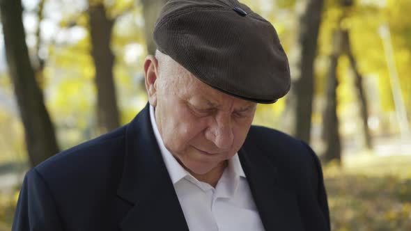 Portrait of Elegant Senior Man Thinking When Writing in Notebook on Park Bench