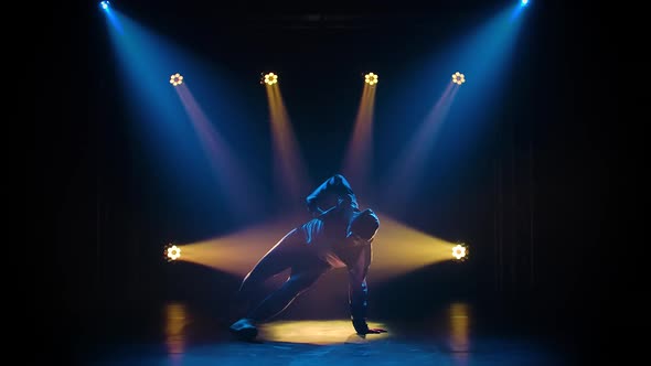 Young Sporty Guy Dancing Break Dance on the Background of Studio Lighting, Silhouette Dancer Man 