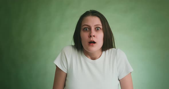 Startled Young Woman Opens Mouth Near Studio Green Wall