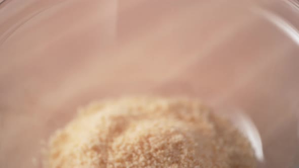 Camera follows adding egg into bread crumb in a bowl. Slow Motion.