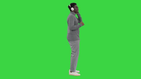 Smiling African American Man in Headphones and Moving To the Music Rhythm on a Green Screen Chroma