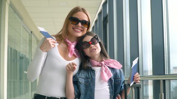 Female and Little Girl Holding Passports and Airline Boarding Pass Tickets