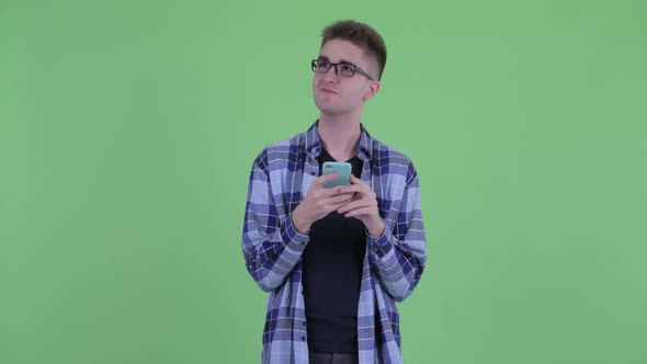 Happy Young Hipster Man Thinking While Using Phone