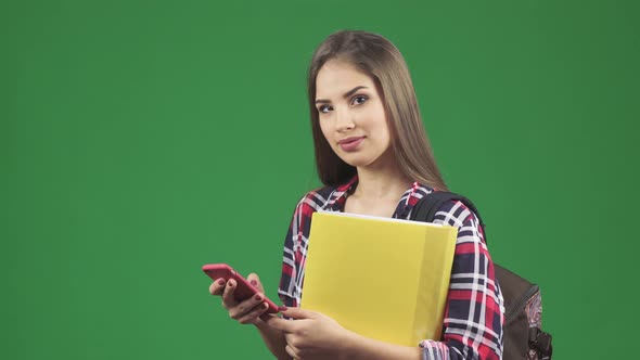 Attractive Young Female Student Using Her Smart Phone Smiling To the Camera