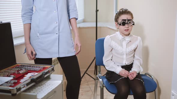 the Child Sits on a Chair at the Oculist and Checks Vision in Special Glasses