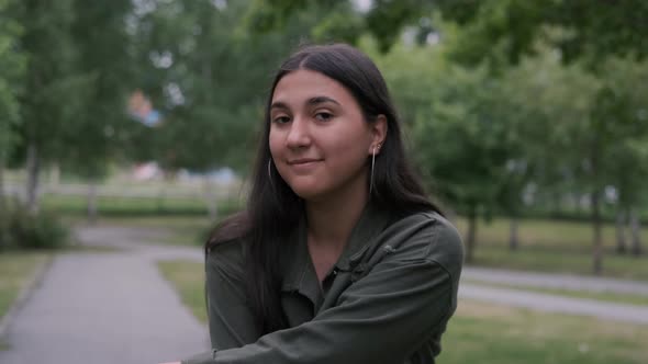 Young Hipster Brunette Girl with Long Hair in a Good Mood Is Dancing in the Park To the Music While