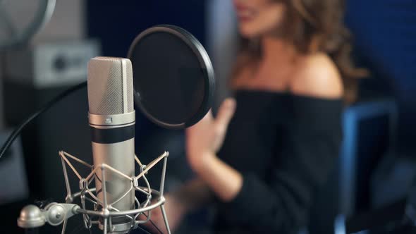 Professional microphone in the recording studio. Background of a singing woman.