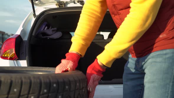 A man unloads winter tires from a car trunk