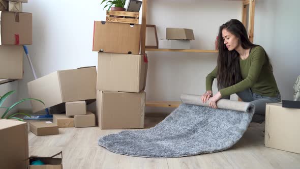 Moving to a New Home Concept Young Latin Woman Collects Carpet and Boxes for Moving and Relocation