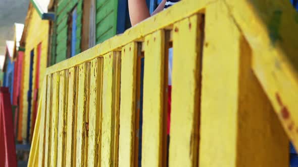 Girl photographing with camera from colorful beach hut