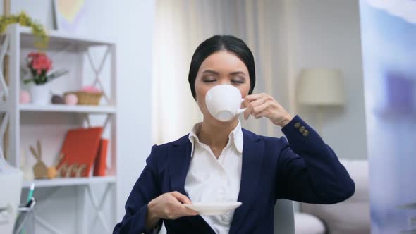 Female Office Worker Enjoying Coffee Taste Imagining Home Comfort, Recreation