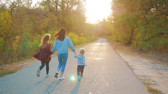 Mother and Two Children Walking in the Park and Enjoying the Beautiful Autumn Nature. Happy Family