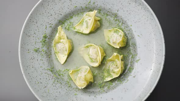 Top View of Soup with Wontons Spinning on a Gray Plate Close Up