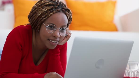 Young Woman Lying on Sofa Looking at Laptop Typing and Browsing Internet