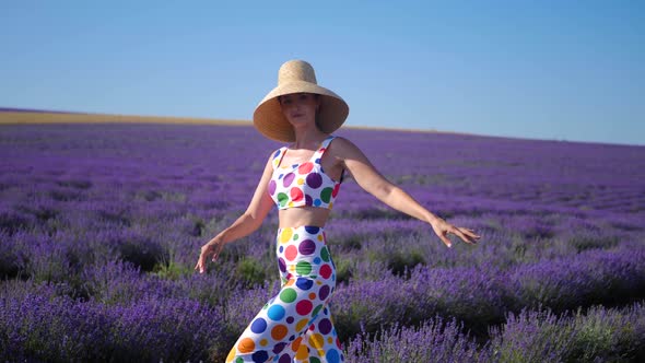 Woman in a Multicolored Suit with Circles and a Hat Holds Large Inflatable