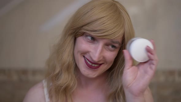 Headshot Portrait Cheerful Travesty Woman Having Fun Closing One Eye with Moisturizer Jar Looking at