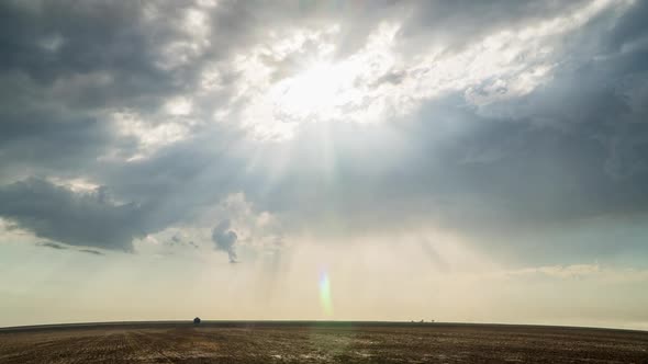 Time lapse of sun rays shining through the clouds moving over flat landscape
