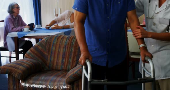 Female doctor assisting senior man to walk with folding walkers