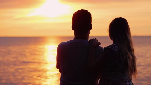 Multi-ethnic Couple in Love Admires the Sunset Over the Ocean