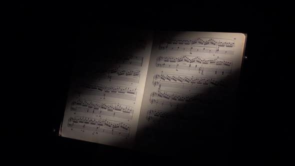 Music Notes with Ray of Light, Hand Scrolls the Sheet, on Black