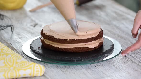 Cream being squeezed onto chocolate cake. Squeezing the cream on the cake.	