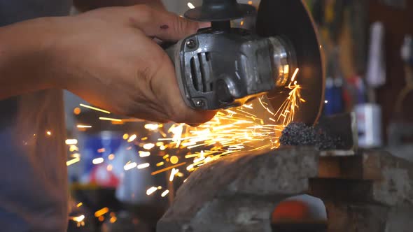 Close Up Male Hands of Adult Welder Cutting Steel Using Electric Grinding Wheel in Workshop