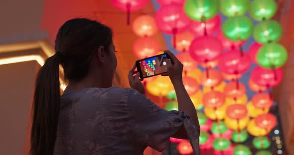 Woman take photo on cellphone with chinese lantern at night