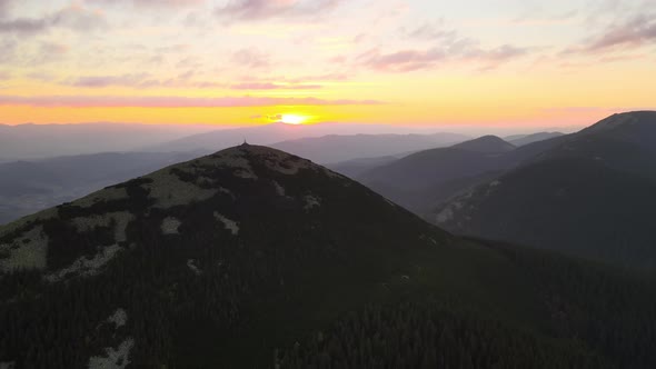 Aerial View of Foggy Evening Over High Peak with Dark Pine Forest Trees at Bright Sunset