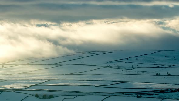 Time-lapse footage of the snow covered fields with their dry stone walls enveloped in low clouds, ne