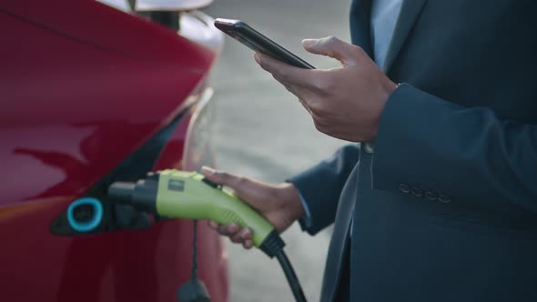 African Man in Suit Solving Urgent Issues on Smartphone While Charging Modern