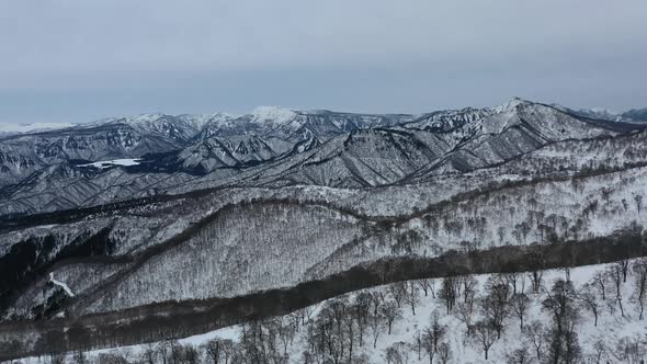 parallel aerial to snowy mountain peaks in nozawa onsen nogano japan in winter
