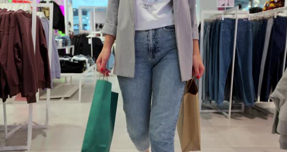 Close Up of Young Woman Walks with Colorful Shopping Bags Around a Department Store