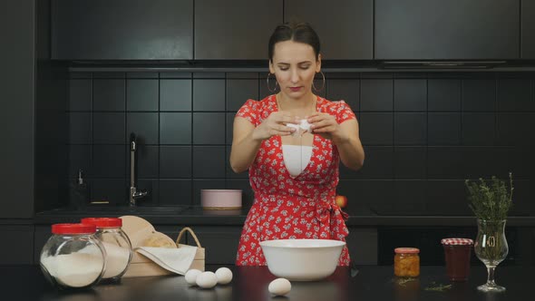 Female breaking eggs into bowl and cooking homemade cake in home modern kitchen. Food concept