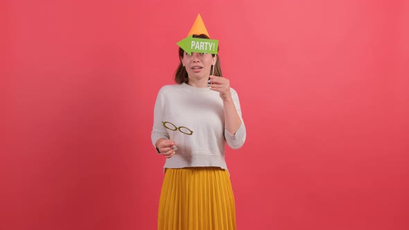 Happy Woman in Party Hat Holding Birthday Accessories on Red Background.