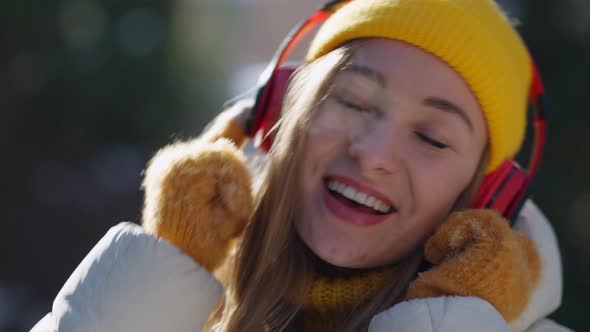 Headshot Portrait of Cheerful Relaxed Caucasian Young Woman Listening to Music in Headphones Dancing