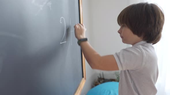 Portrait of Joyful Caucasian Schoolboy Solving Math Problem on School Board and Smiling Pointing at