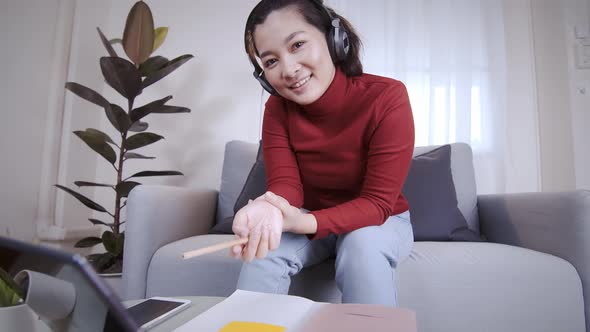 Freelance woman redshirt using tablet with headphone for meeting online at home