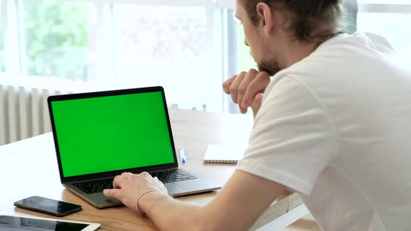 Handsome Specialist Working on Laptop Computer with Green Screen Mock Up Display at Home