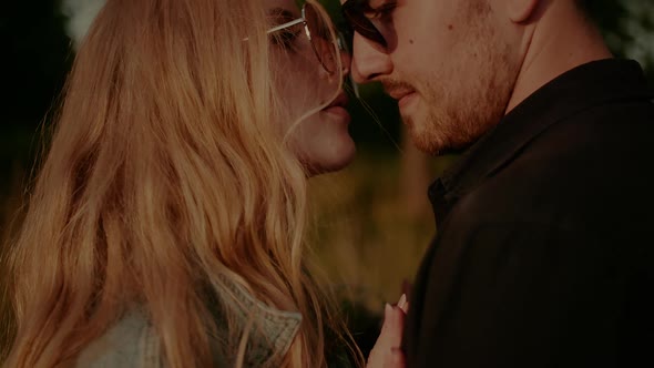 Woman Supporting Young Man Outdoors at Sunset