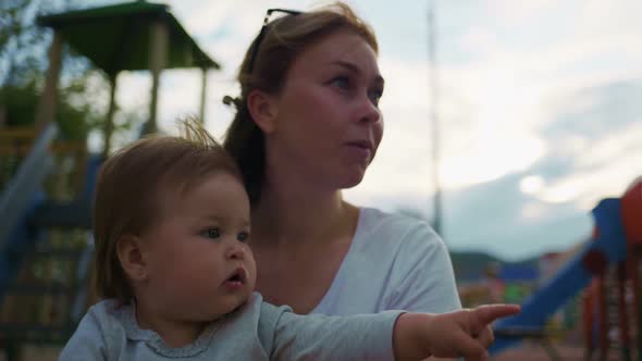 The kindergarten teacher holds the baby on the handles, talking to him.