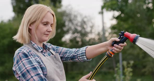 Middleaged Woman Watering Plants in Her Garden