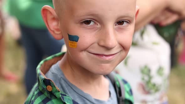 close up of smiling child with painted Ukrainian flag on face. Protest against Russian war invasion 