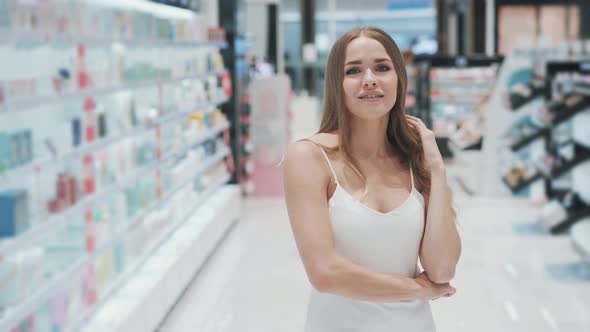 Smiling Positive Young Caucasian Girl Shopper in Cosmetics and Perfumery Store